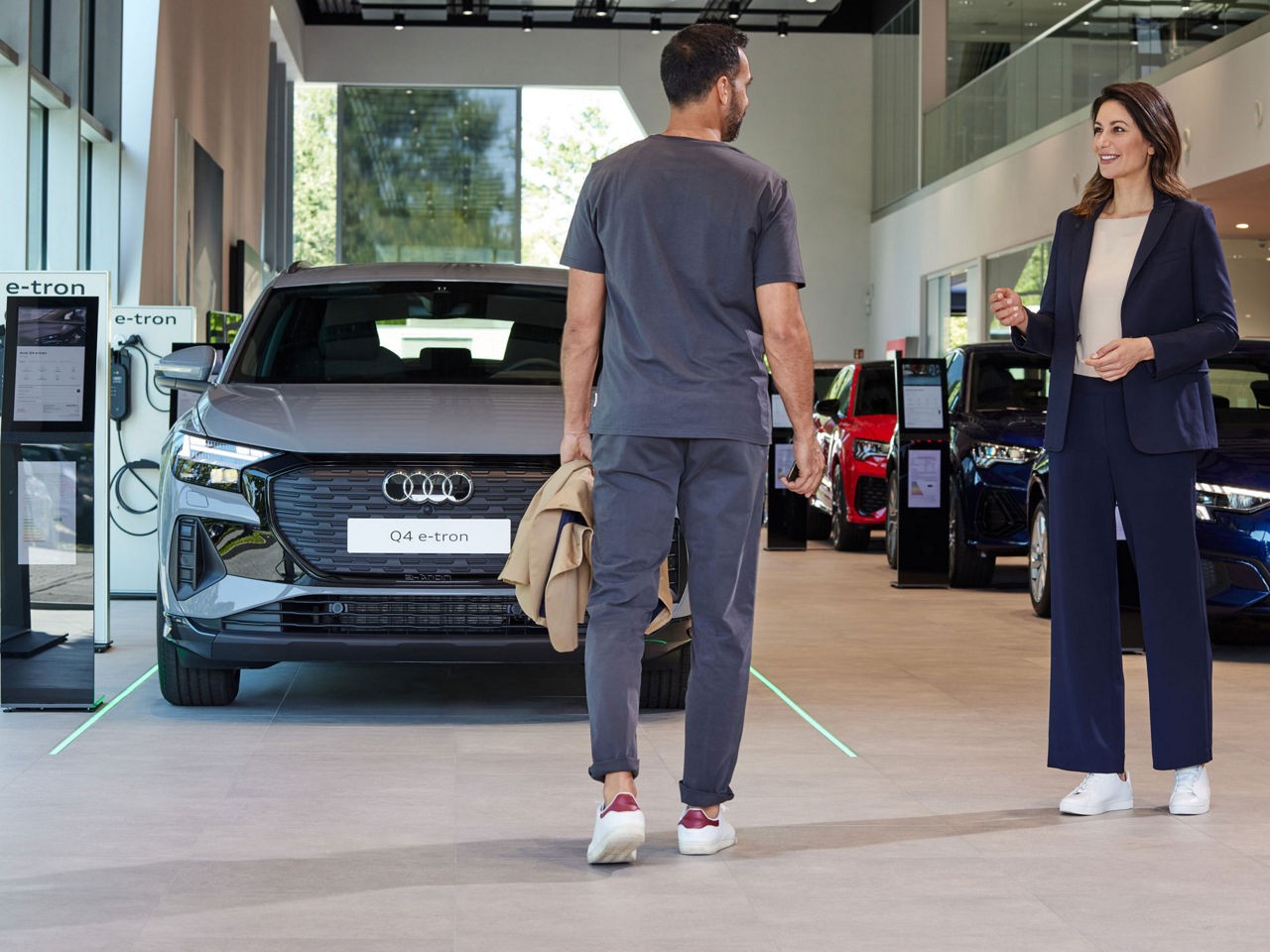 a woman and a man in an Audi dealership stand in front of several vehicles